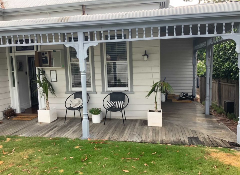 A worker's cottage-style home with a worn timber porch