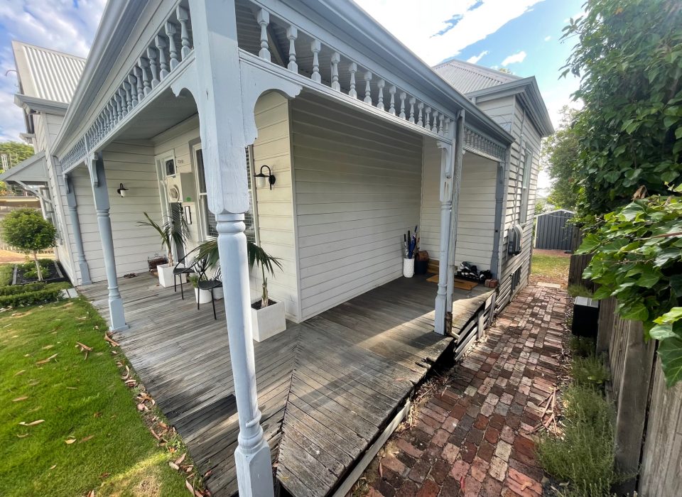 A worker's cottage-style home with a worn timber porch