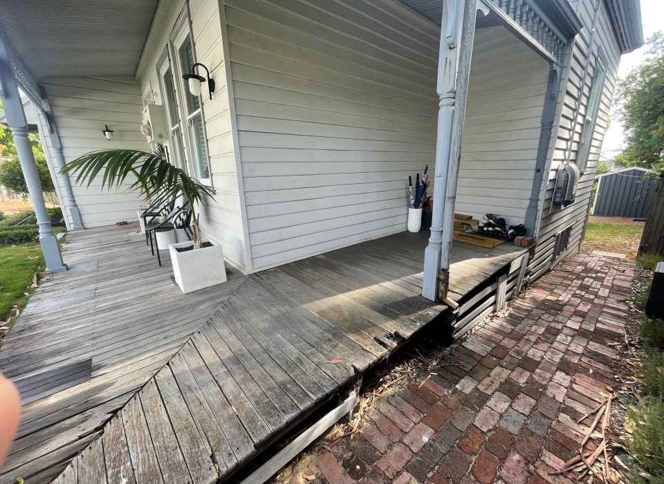 A worker's cottage-style home with a worn timber porch