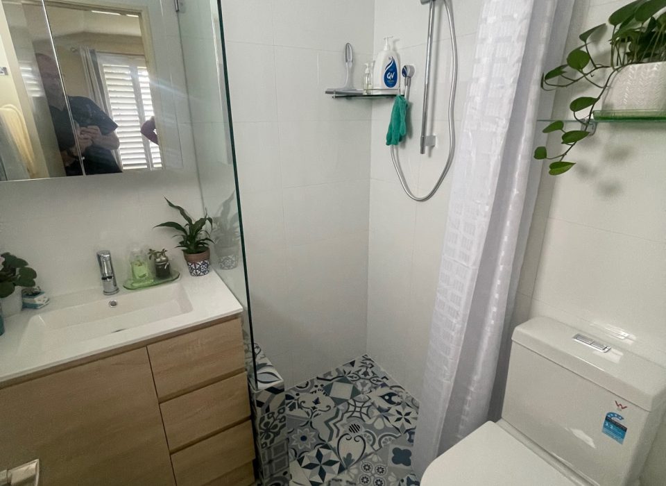 A renovated bathroom with blue and white patterned floor tiling and a walk-in shower