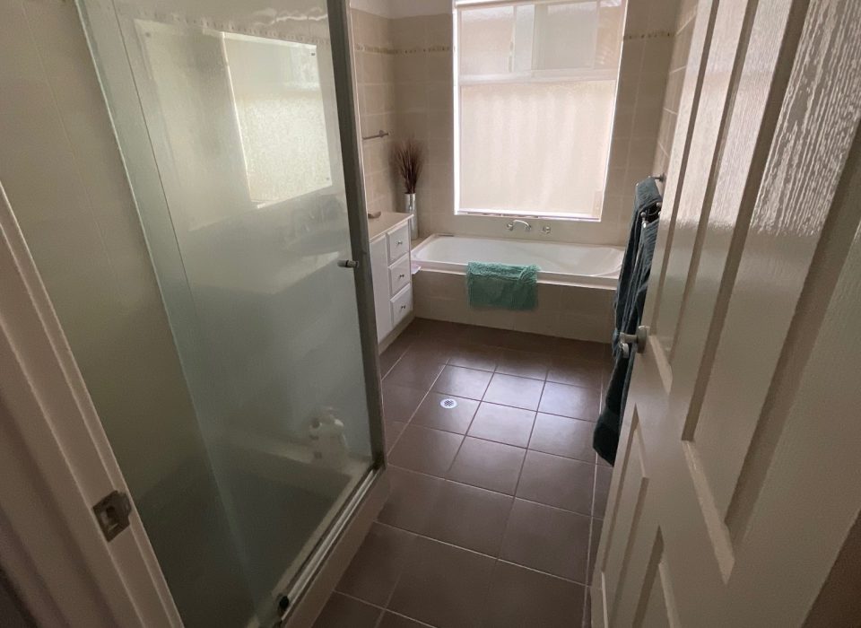 An outdated bathroom with a shower enclosure and inset bathtub