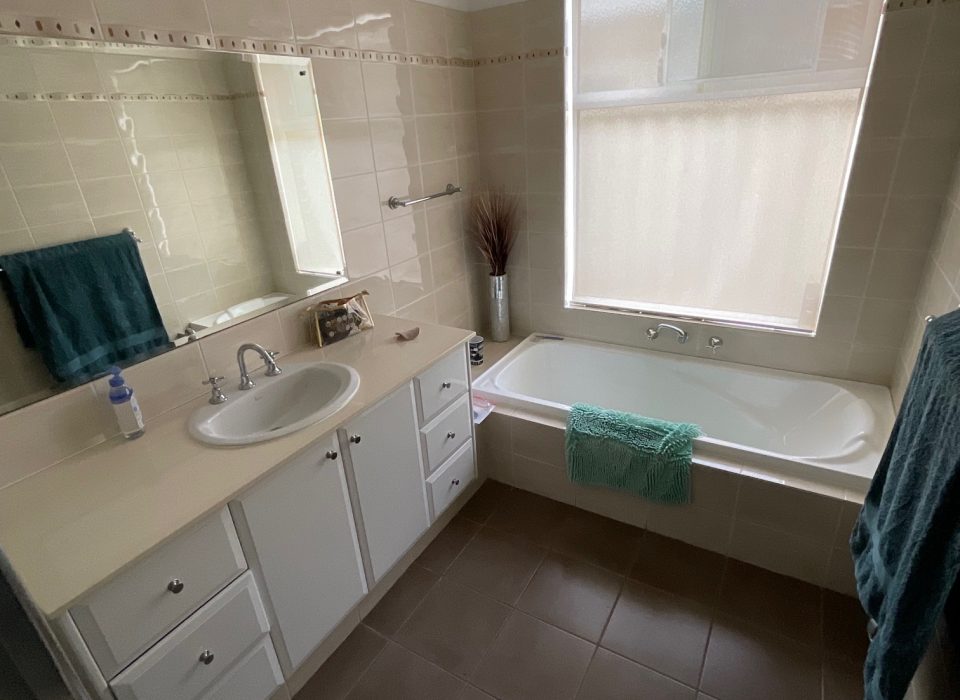 An outdated bathroom with a shower enclosure and inset bathtub
