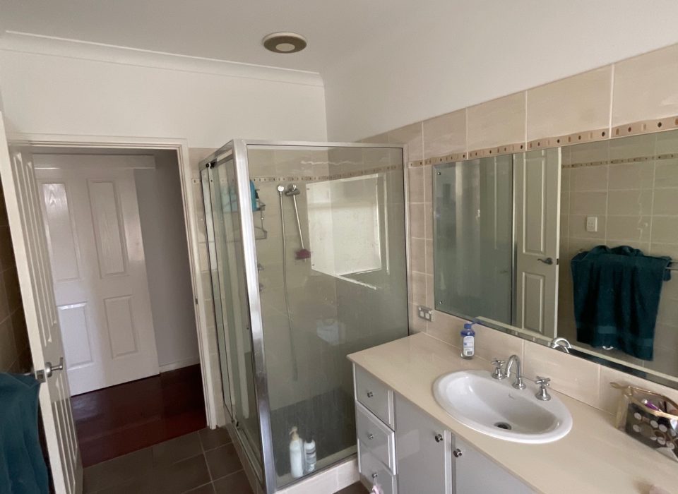 An outdated bathroom with a shower enclosure and inset bathtub