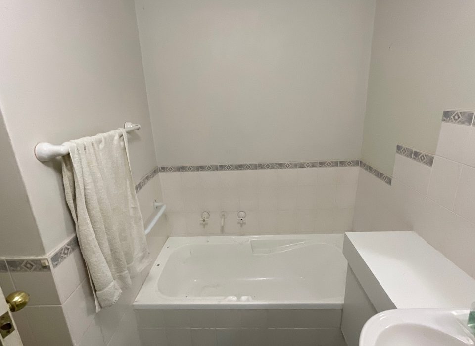 An old bathroom with blue floor tiling and a bathtub
