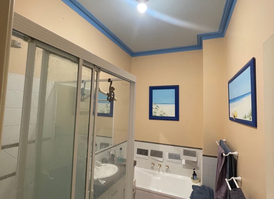 An old bathroom with a shower enclosure, small vanity, and bathtub